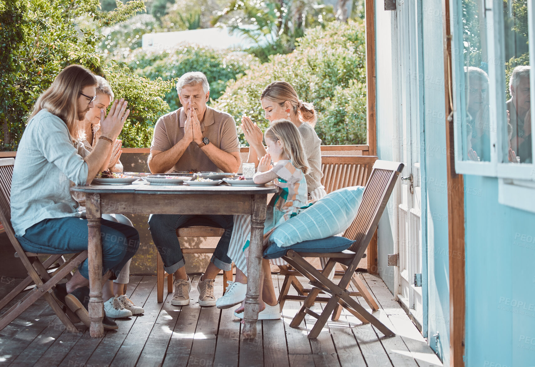 Buy stock photo Lunch, backyard and family in prayer together with gratitude, faith and weekend gathering event at table on patio. Men, women and child giving thanks with worship, food and spiritual solidarity