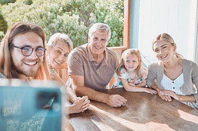 Buy stock photo Shot of a handsome young man sitting with his family and using his cellphone to take selfies