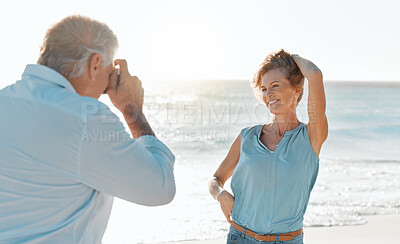 Buy stock photo Shot of a man taking a picture of his wife while at the beach