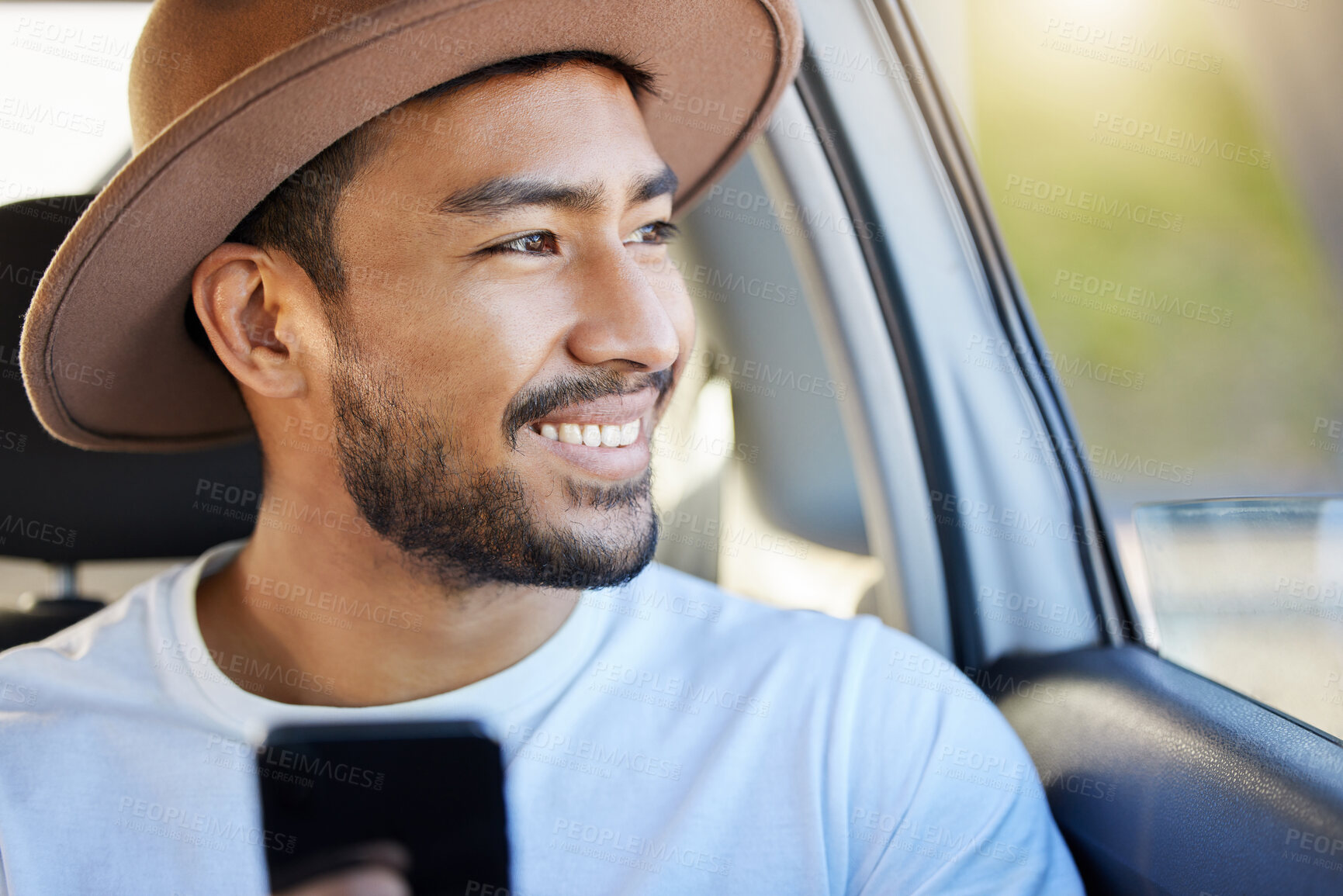 Buy stock photo Shot of a young man sitting in a car while using his phone