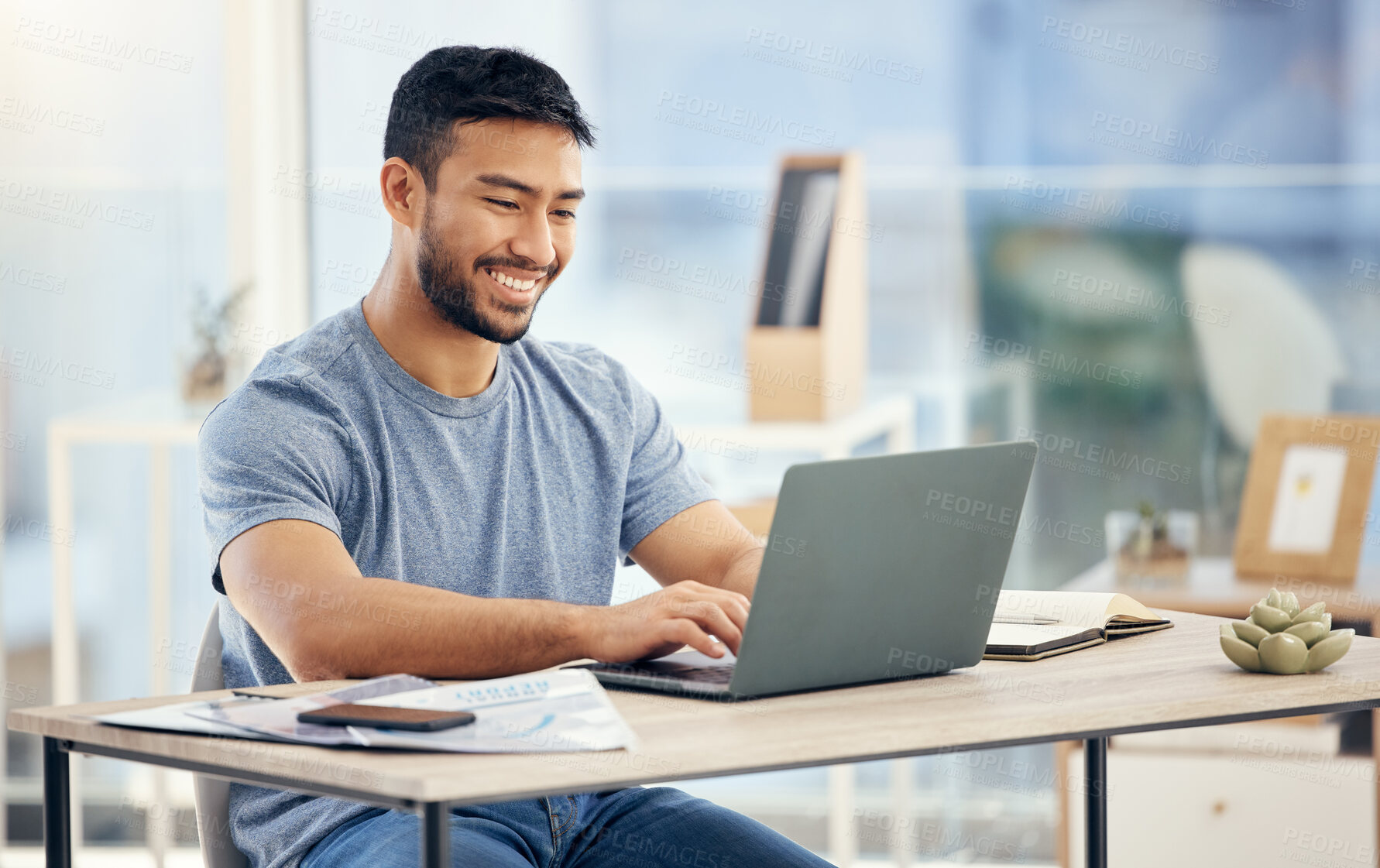 Buy stock photo Shot of a young businessman using a laptop in an office at work