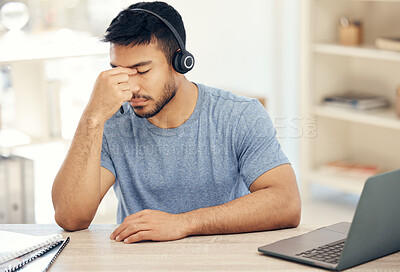 Buy stock photo Shot of a young male call center agent suffering from a headache while at work