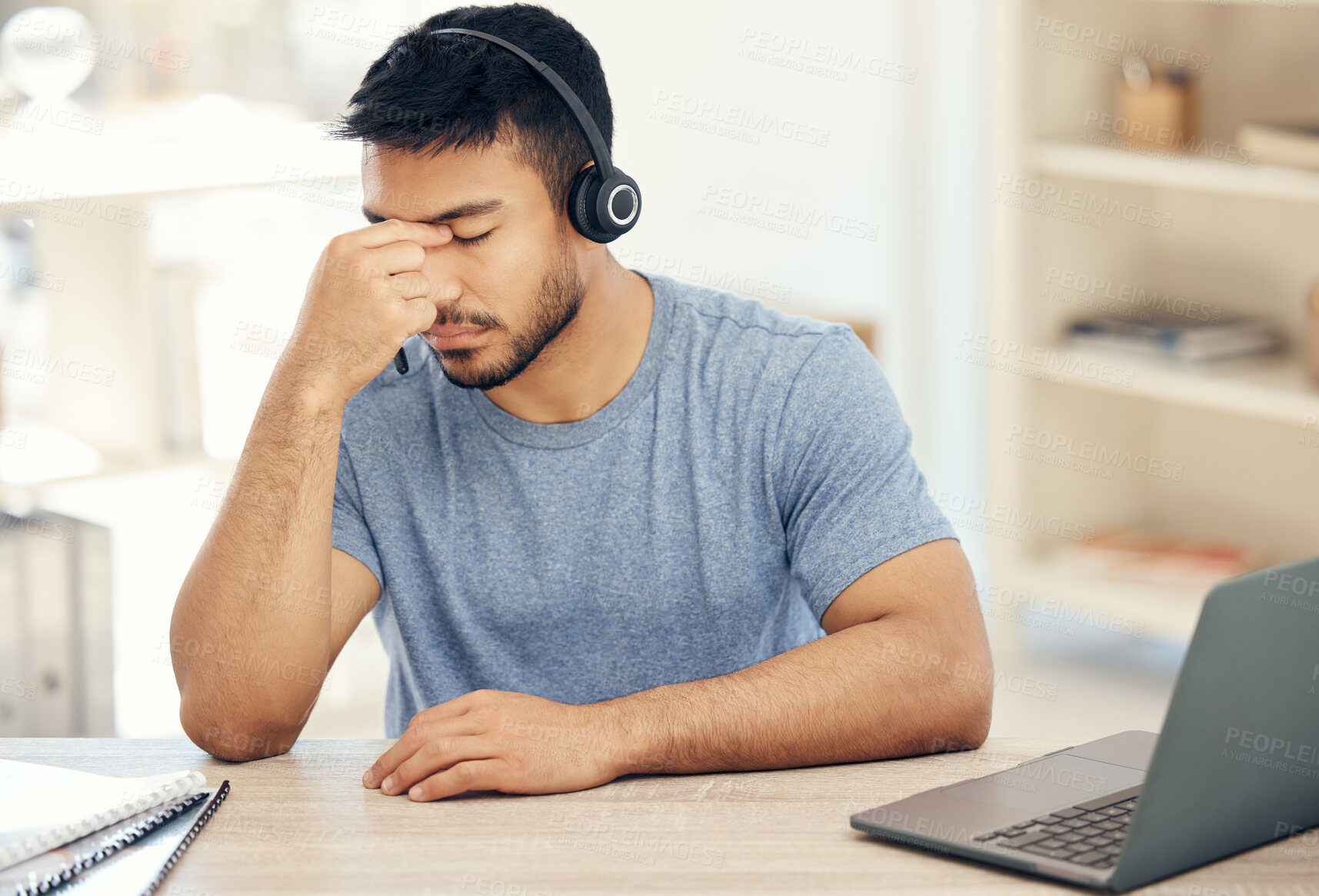 Buy stock photo Shot of a young male call center agent suffering from a headache while at work