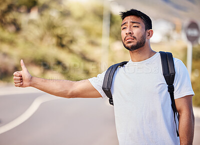 Buy stock photo Asian man, road and desperate with thumbs up for hitchhiking for ride or journey home in California. Male person, backpack and sad or tired with stopping cars or transport and travel to destination