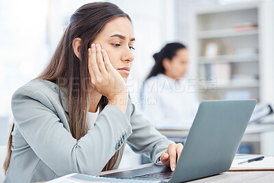 Buy stock photo Shot of a young businesswoman looking bored while using a laptop in an office at work