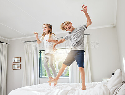 Buy stock photo Shot of a brother and sister having fun while jumping on a bed together at home