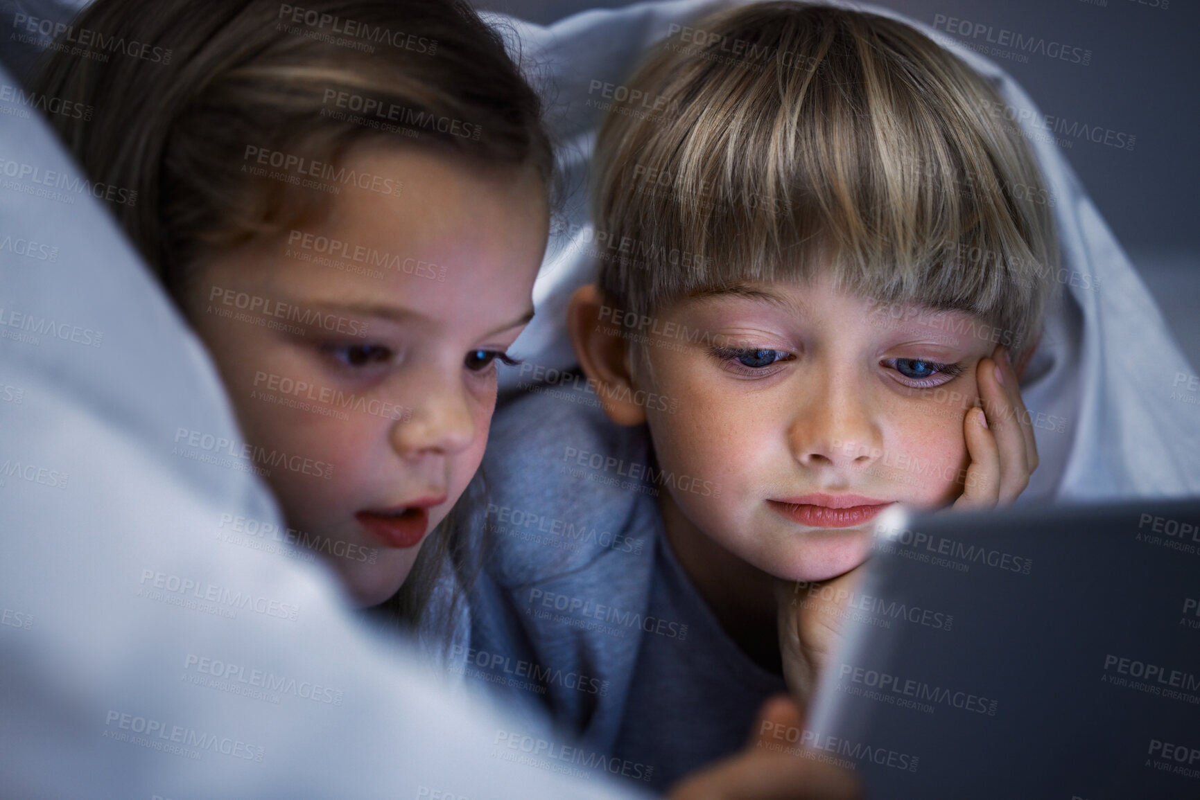 Buy stock photo Shot of a brother and sister using a tablet in bed at night
