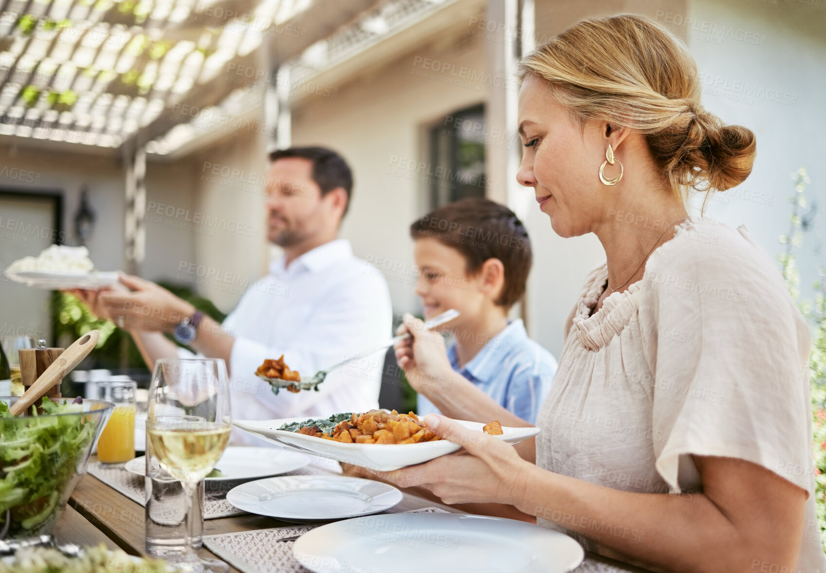 Buy stock photo Family lunch, woman and serving at table for food, reunion and caring in backyard. Mom, people and dishing at outdoor table for meal, help or hungry on weekend with sharing or support in relationship