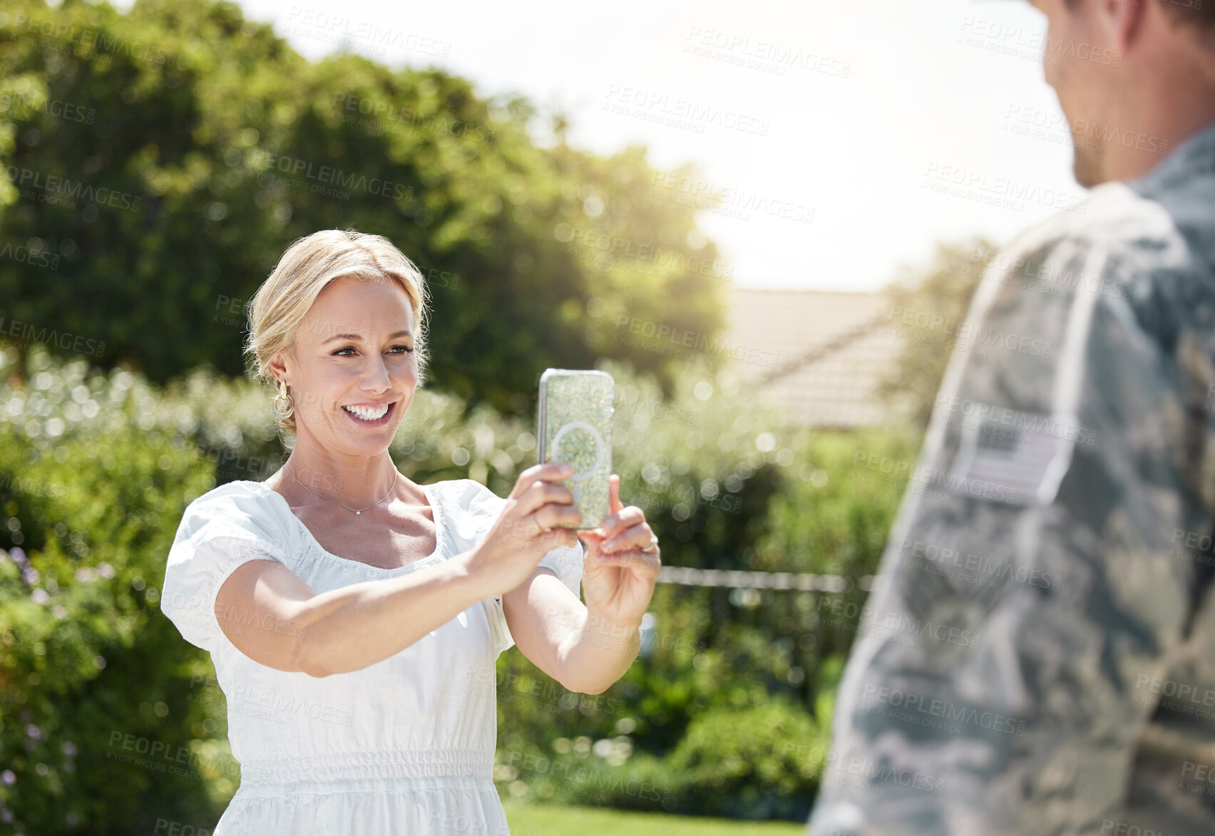 Buy stock photo Phone, couple and happy woman take photo of soldier outdoor to celebrate return of hero from army. Smile, picture and war veteran in military with man for love, memory and welcome patriot in nature