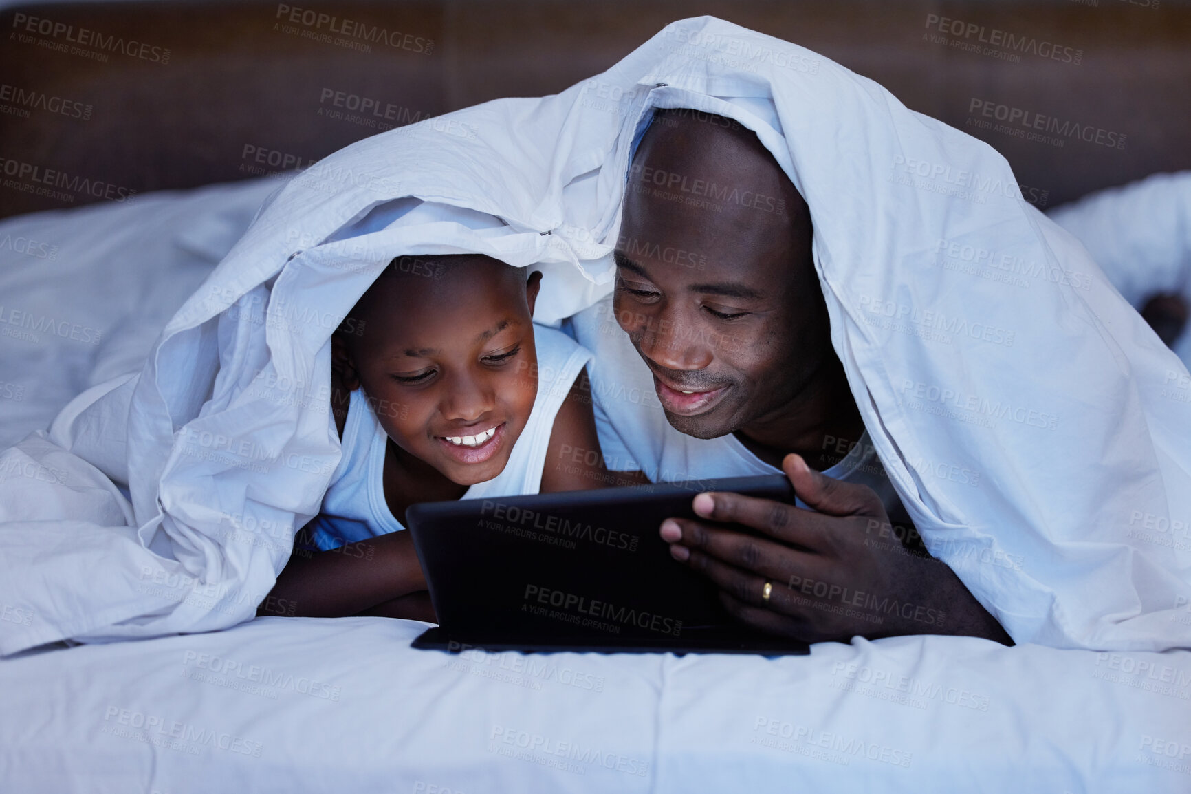 Buy stock photo Shot of a Father and son using a tablet in bed at night