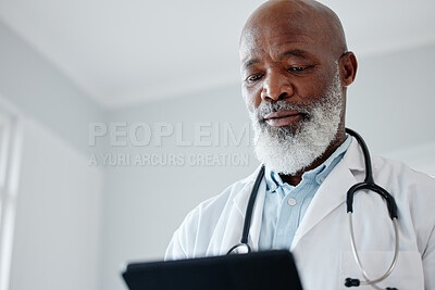 Buy stock photo Low angle shot of a mature doctor using a digital tablet in a medical office