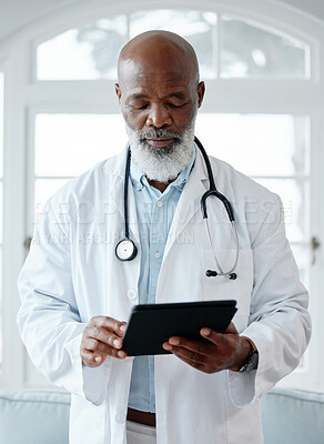 Buy stock photo Shot of a mature doctor using a digital tablet in a medical office