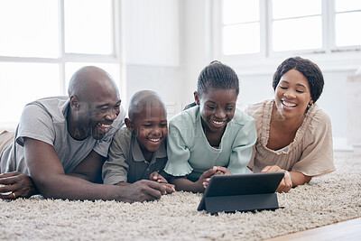 Buy stock photo Shot of a family using s tablet while laying on the floor at home