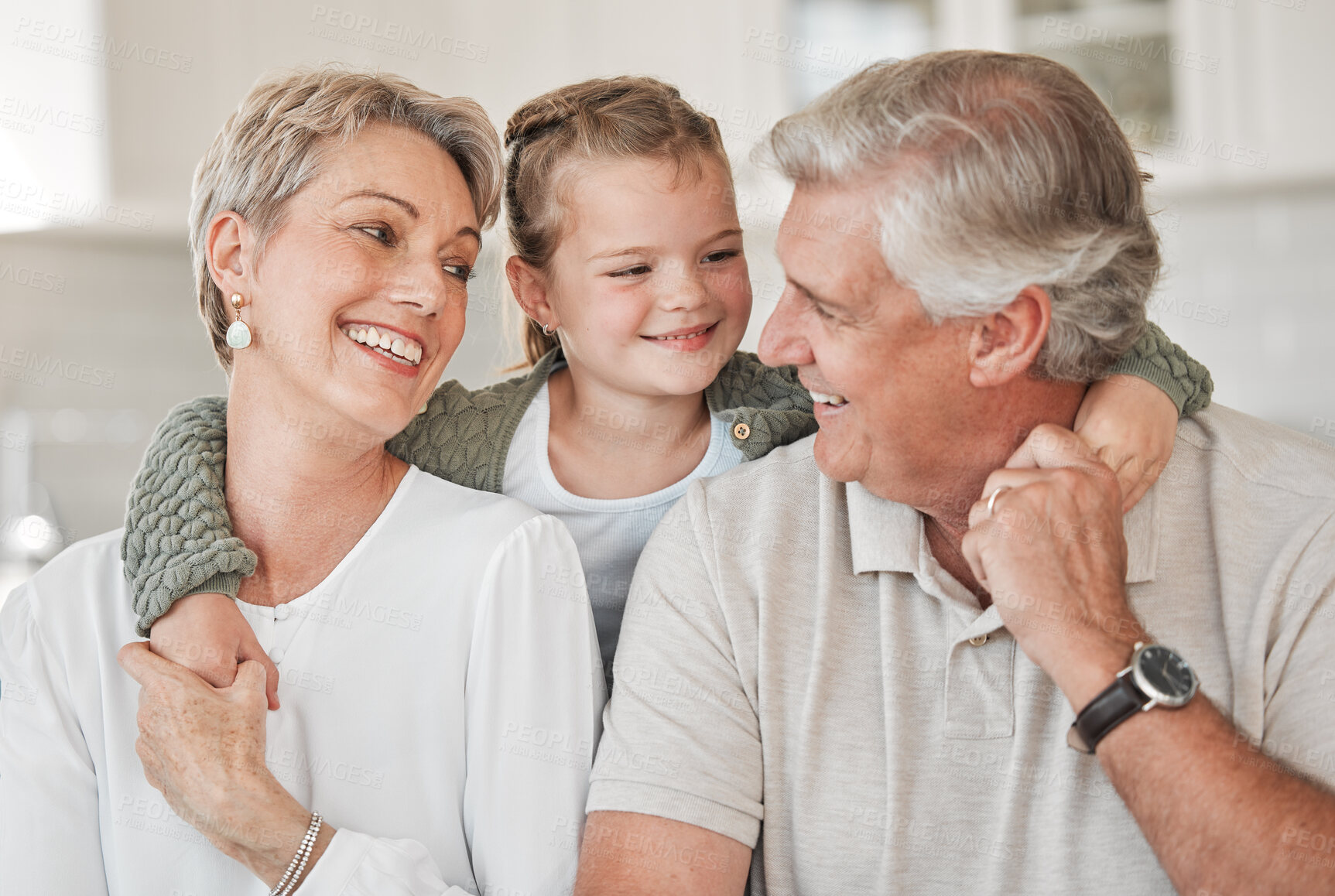 Buy stock photo Home, grandparents and child with smile for hug, connection and bonding together as happy family. House, grandmother and grandfather with girl for security, love and embrace on sofa by living room