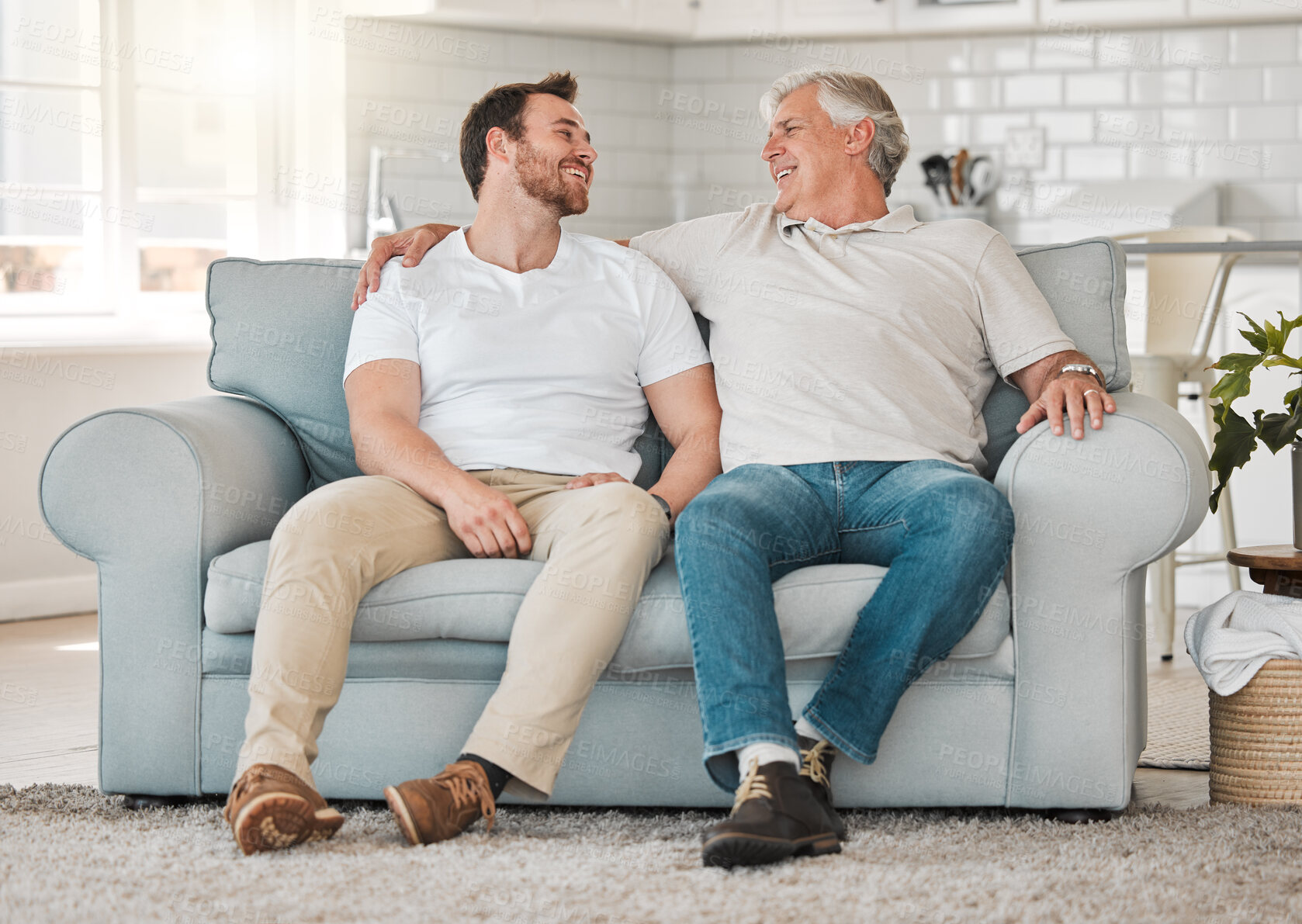 Buy stock photo Laughing, senior father and man on sofa for talking, connection and bonding together with hug in home. Happy family, elderly dad and adult son on couch with smile, support and security in house