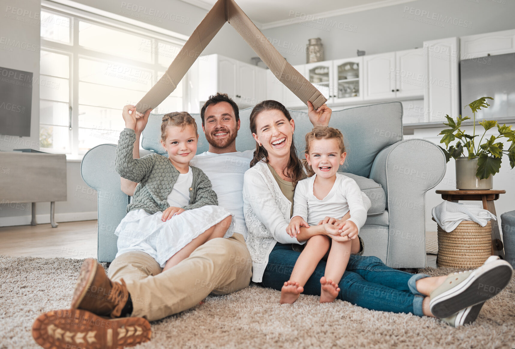 Buy stock photo Portrait of a young family sitting on the lounge floor under a cardboard fort together at home