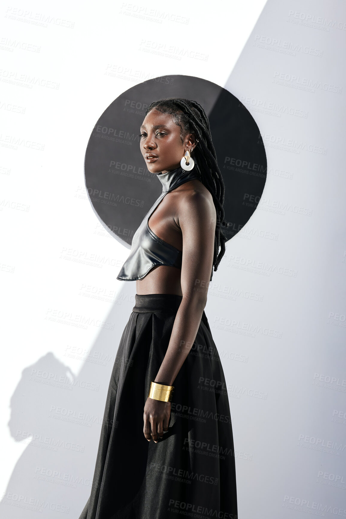 Buy stock photo Shot of an attractive young woman posing in a black outfit against a wall with a circle on it