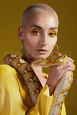 Buy stock photo Shot of a fashionable woman holding a snake while modelling a yellow concept