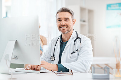 Buy stock photo Portrait of a mature doctor working on a computer in a medical office