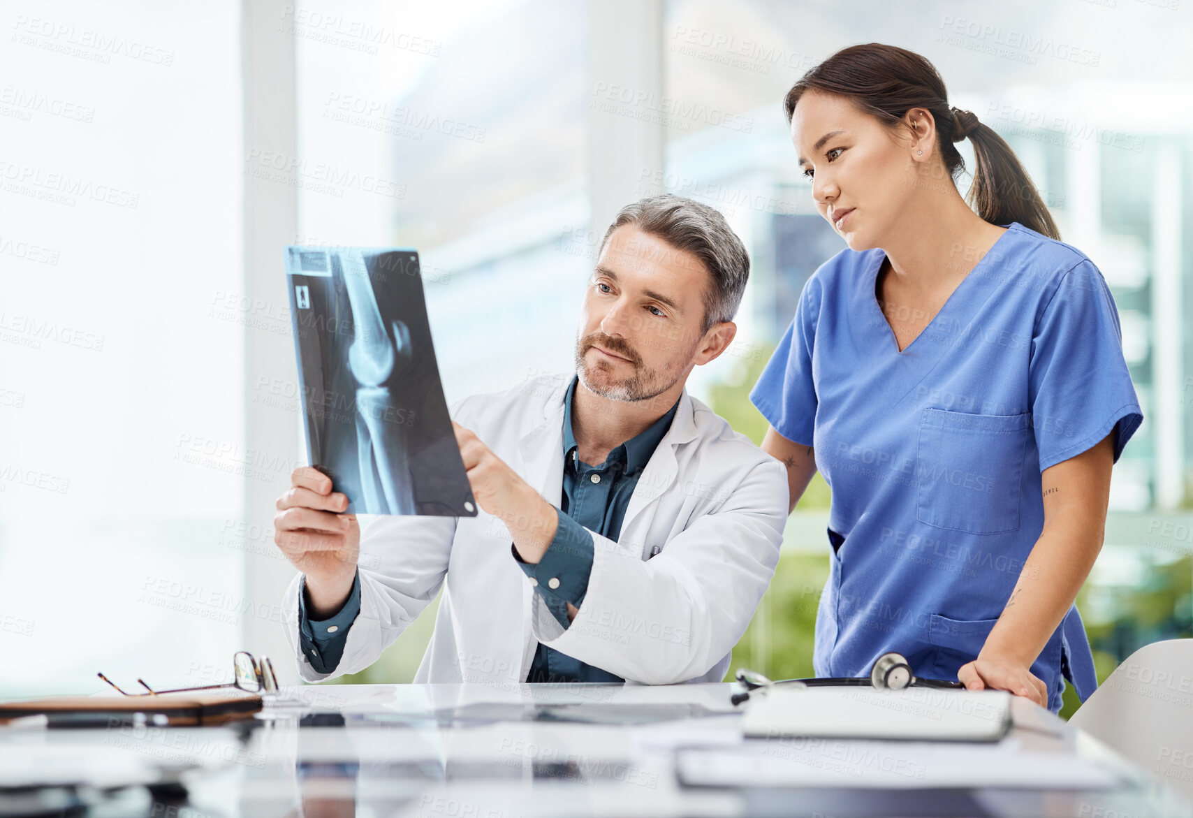 Buy stock photo Shot of two doctors reviewing a patient's x-ray