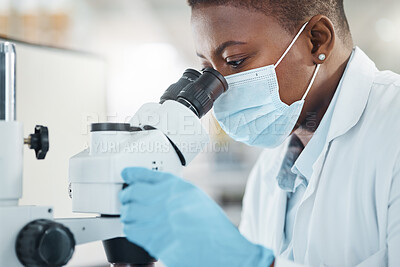 Buy stock photo Shot of a young woman using a microscope in a lab