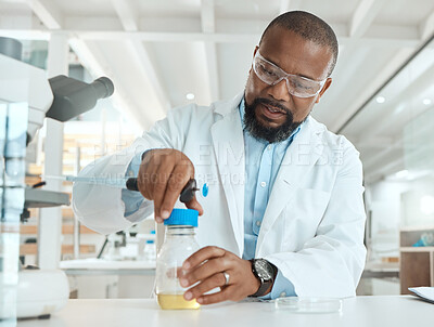 Buy stock photo Shot of a handsome mature scientist sitting alone in his laboratory and opening a bottle of liquid for testing