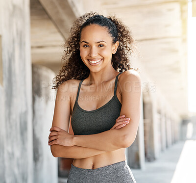 Buy stock photo Shot of an attractive young woman standing alone in the city with her arms folded during her outdoor workout