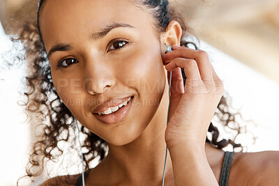 Buy stock photo Shot of an attractive young woman putting her earphones in during her outdoor workout in the city