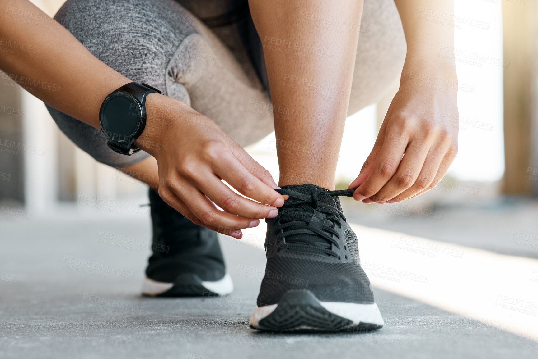 Buy stock photo Cropped shot of an unrecognisable woman crouching down to tie her shoelaces during her outdoor workout