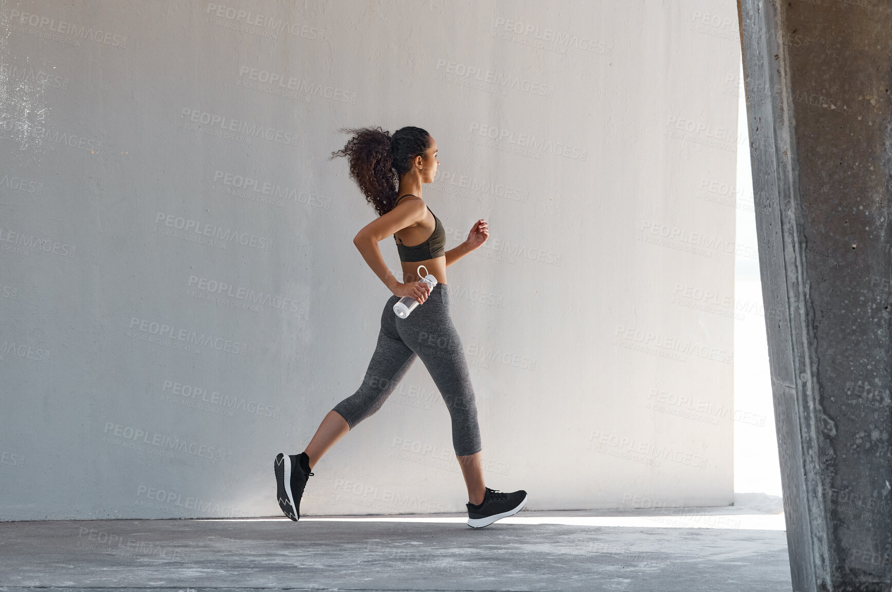 Buy stock photo Full length shot of a young woman running alone during her outdoor workout in the city