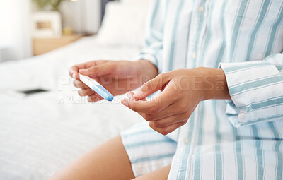 Buy stock photo Shot of an unrecognizable woman holding a pregnancy test at home