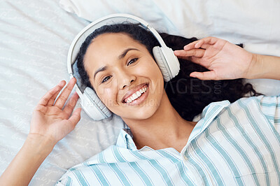 Buy stock photo Shot of a young woman listening to music while sitting on her bed at home