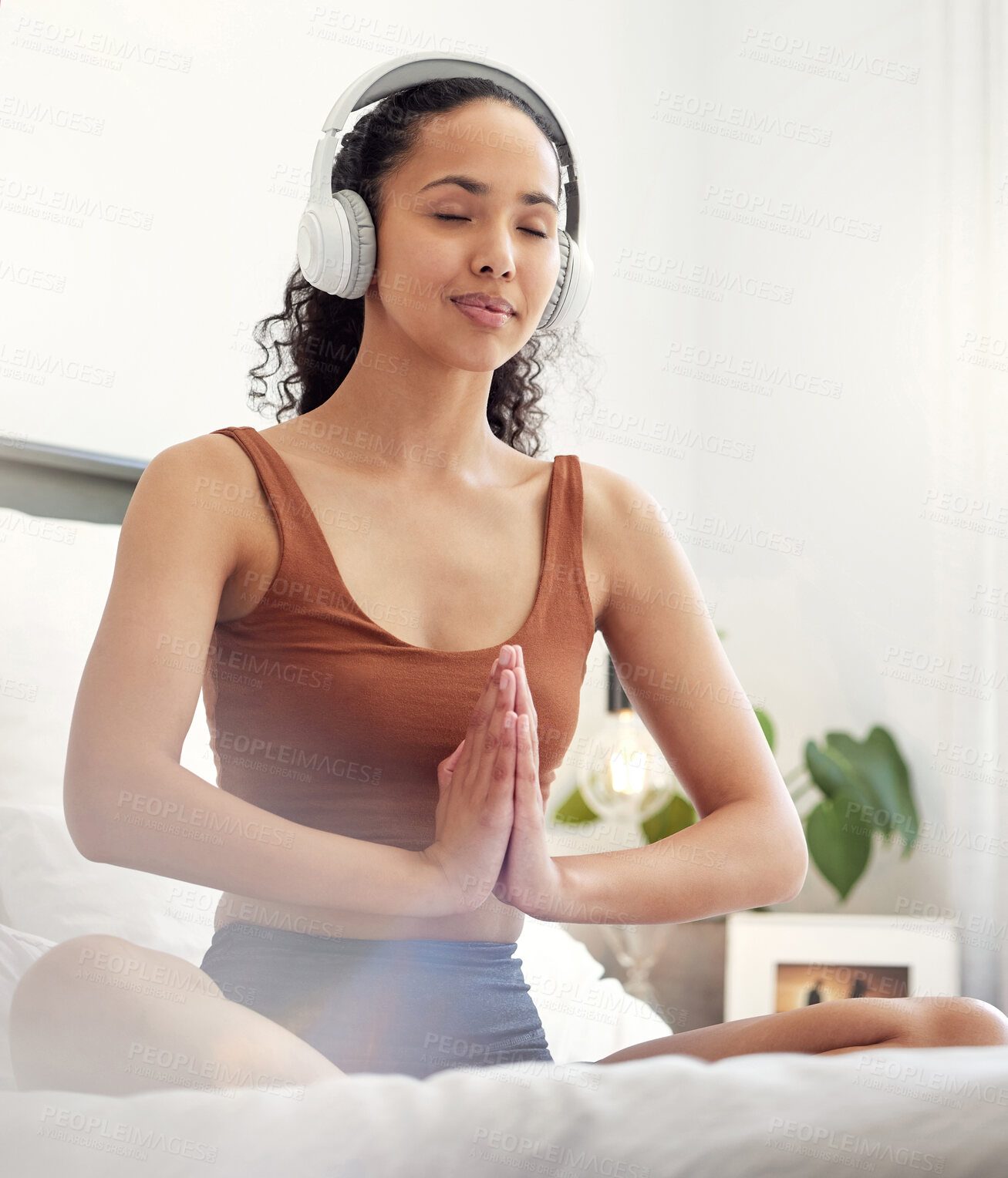 Buy stock photo Shot of a young woman praying while sitting on her bed at home