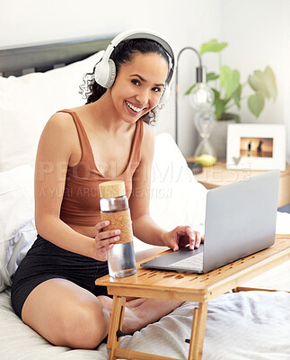 Buy stock photo Shot of a young woman using a laptop while sitting on her bed at home