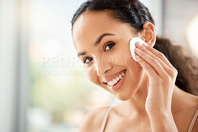 Buy stock photo Shot of a young woman using a cotton pad to clean her face in a bathroom at home