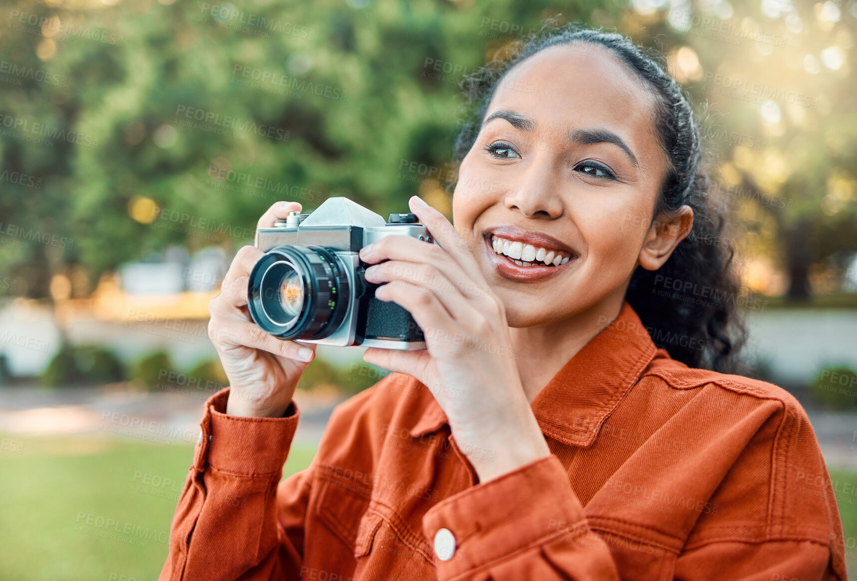 Buy stock photo Shot of a young woman holding her camera while standing outside