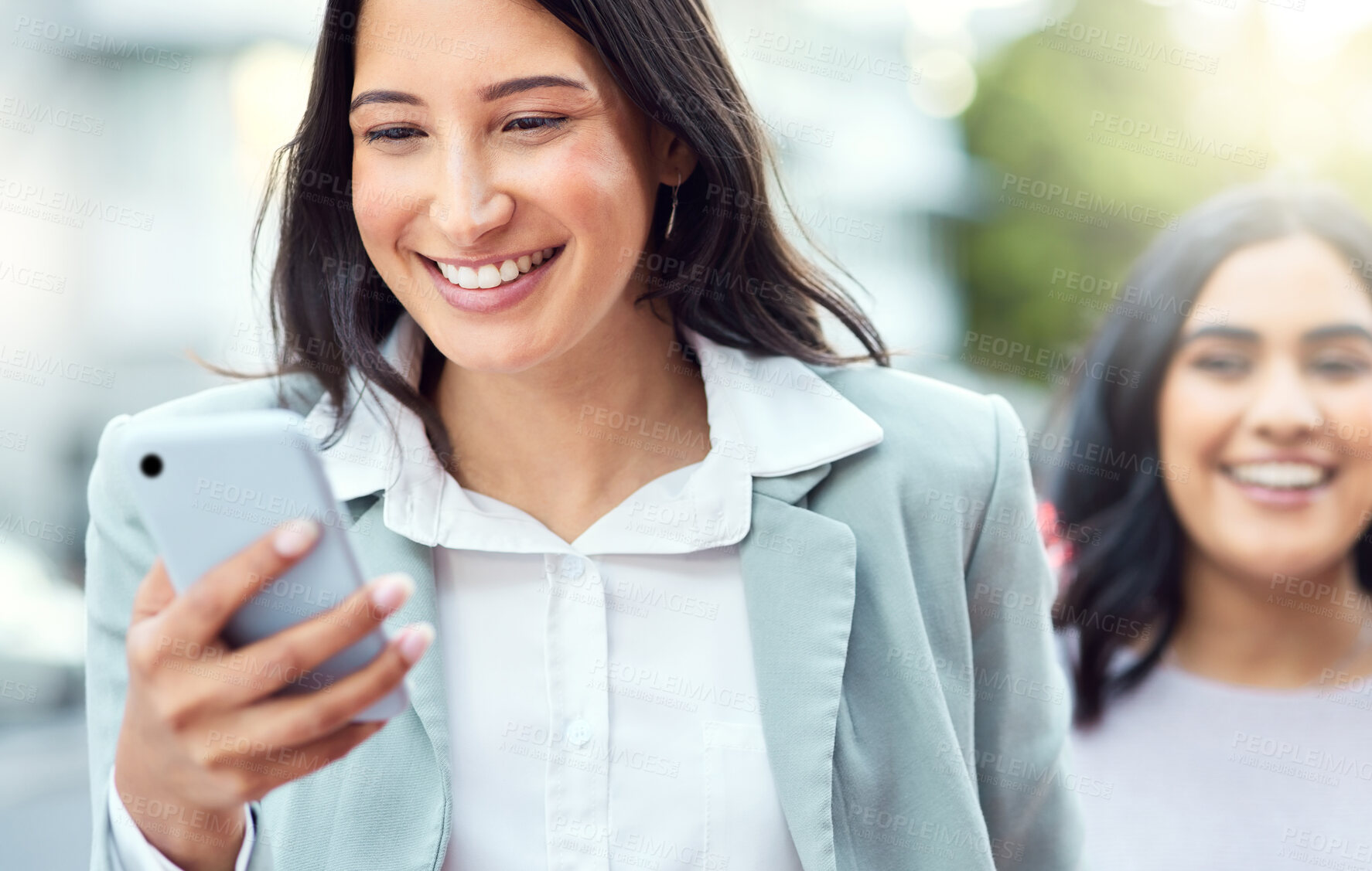 Buy stock photo Shot of a young businesswoman using a smartphone against an urban background