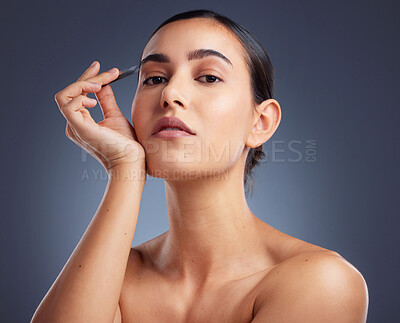 Buy stock photo Studio shot of a beautiful woman tweezing her eyebrows