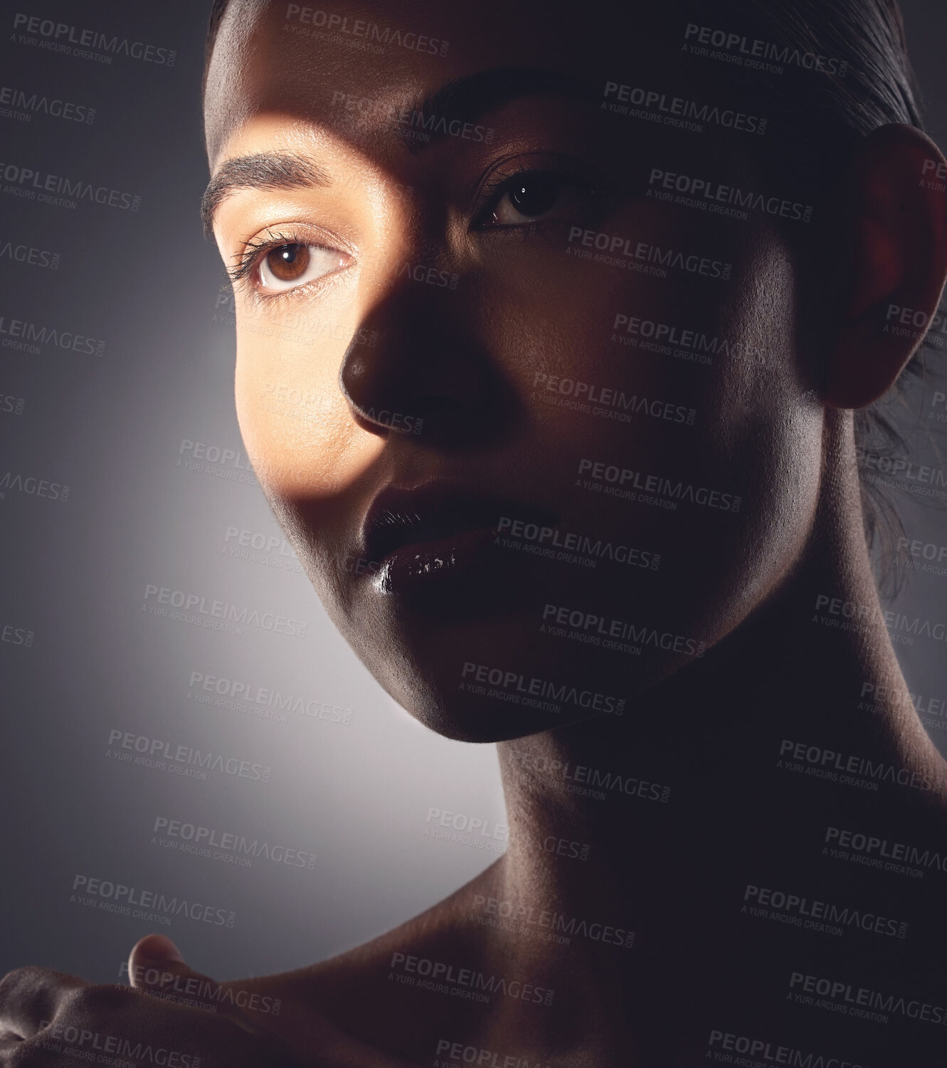 Buy stock photo Studio shot of a beautiful young woman posing with light beam against her face