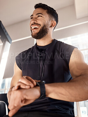 Buy stock photo Shot of a sporty young man checking his watch while exercising in a gym