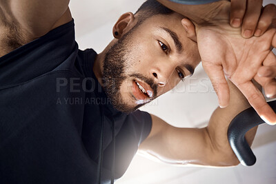 Buy stock photo Low angle shot of a sporty young man taking a break while exercising in a gym