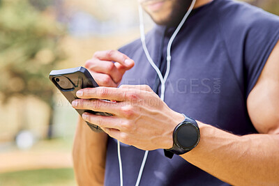 Buy stock photo Closeup shot of an unrecognisable man wearing earphones and using a cellphone while exercising outdoors
