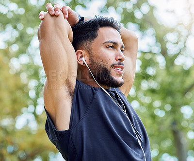 Buy stock photo Shot of a sporty young man stretching his arms while exercising outdoors