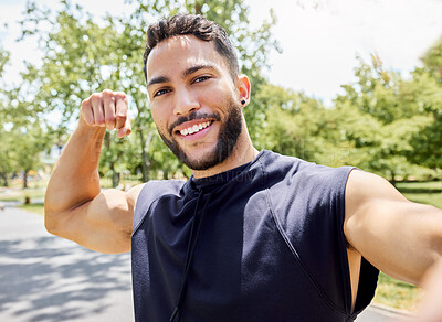 Buy stock photo Portrait of a sporty young man flexing his bicep and taking selfies while exercising outdoors