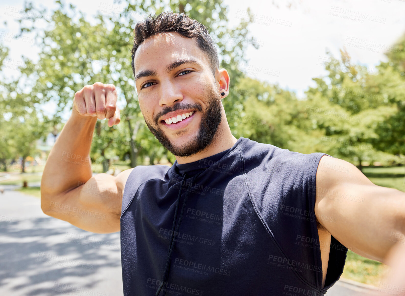 Buy stock photo Portrait of a sporty young man flexing his bicep and taking selfies while exercising outdoors