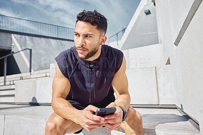 Buy stock photo Shot of a sporty young man using a cellphone while exercising outdoors