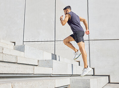 Buy stock photo Low angle shot of a sporty young man running up a staircase while exercising outdoors
