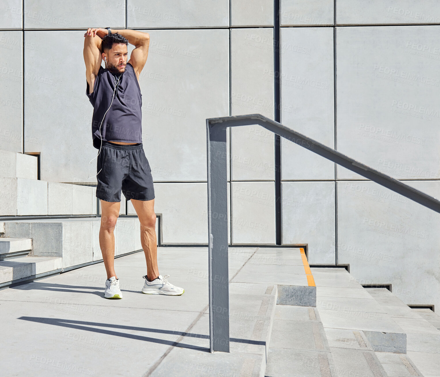 Buy stock photo Shot of a sporty young man listening to music and stretching his arms while exercising outdoors