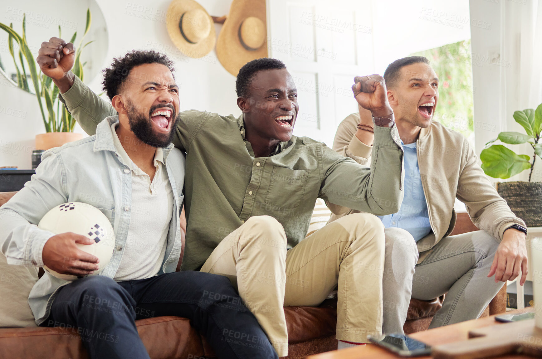 Buy stock photo Shot of three male friends watching something together while sitting on a couch