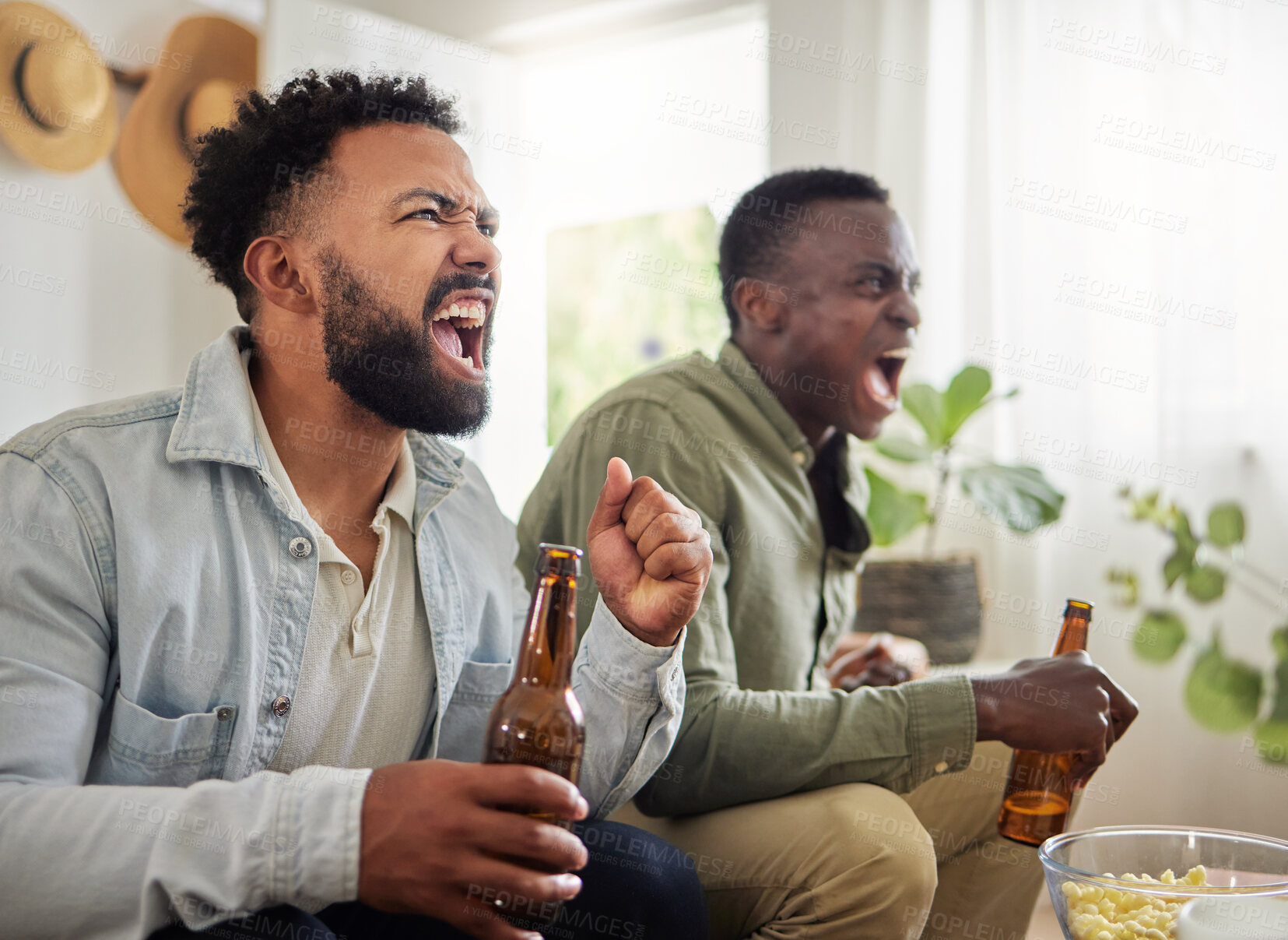 Buy stock photo Shot of two male friends looking cheerful while drinking beers and sitting together